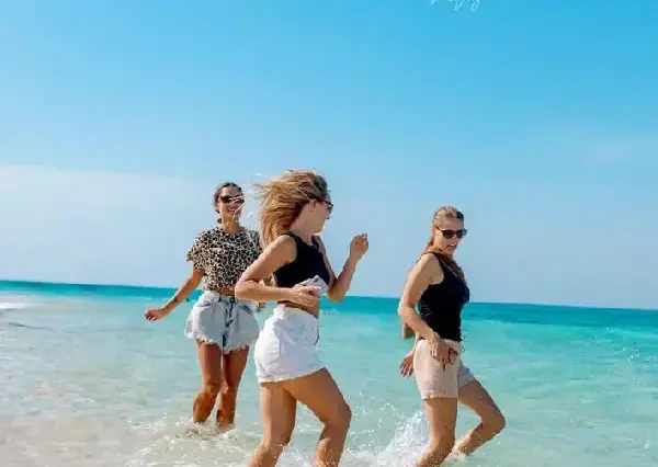 Happy girls running on the white sandy shores of Paradise Island, Hurghada.